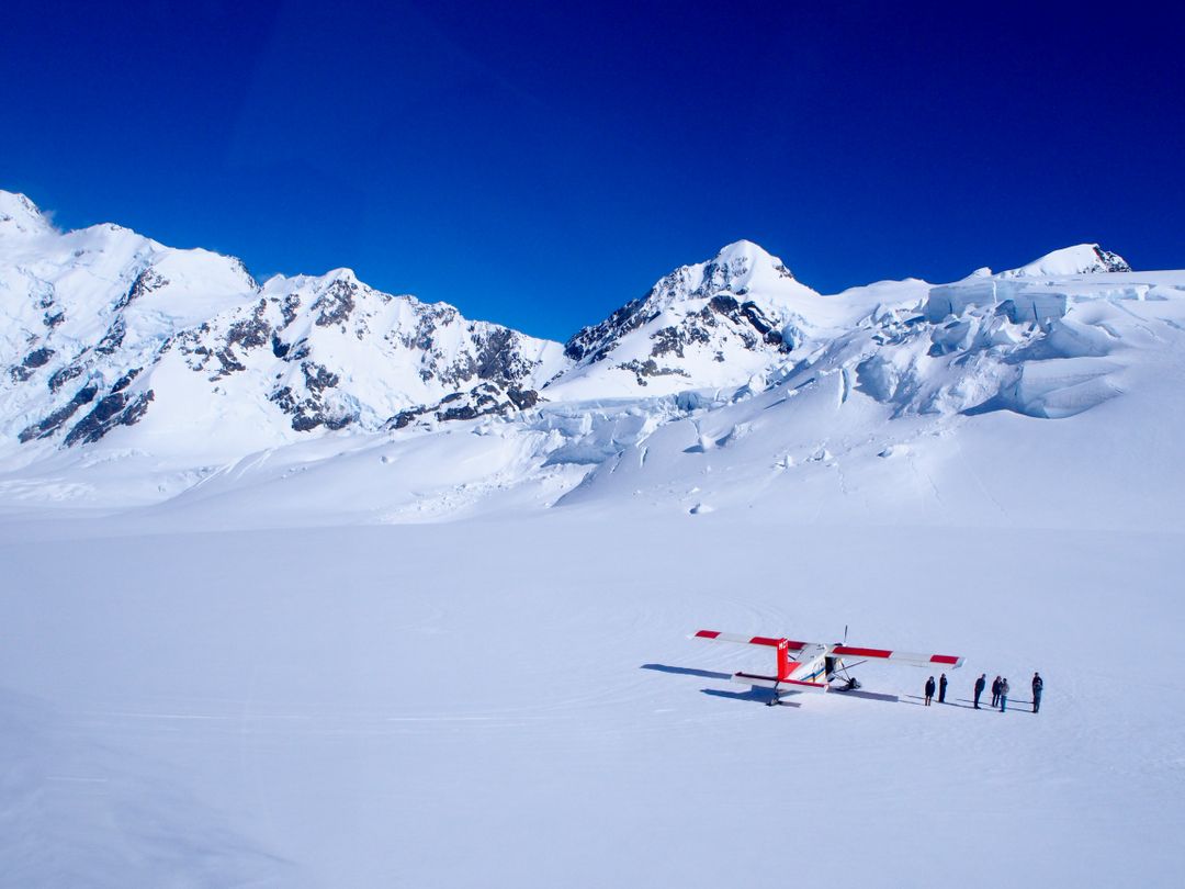 Tourists Beside Red Plane on Snow Covered Mountain Landscape - Free Images, Stock Photos and Pictures on Pikwizard.com