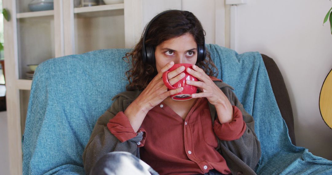 Woman Relaxing at Home with Cup of Coffee Wearing Headphones - Free Images, Stock Photos and Pictures on Pikwizard.com