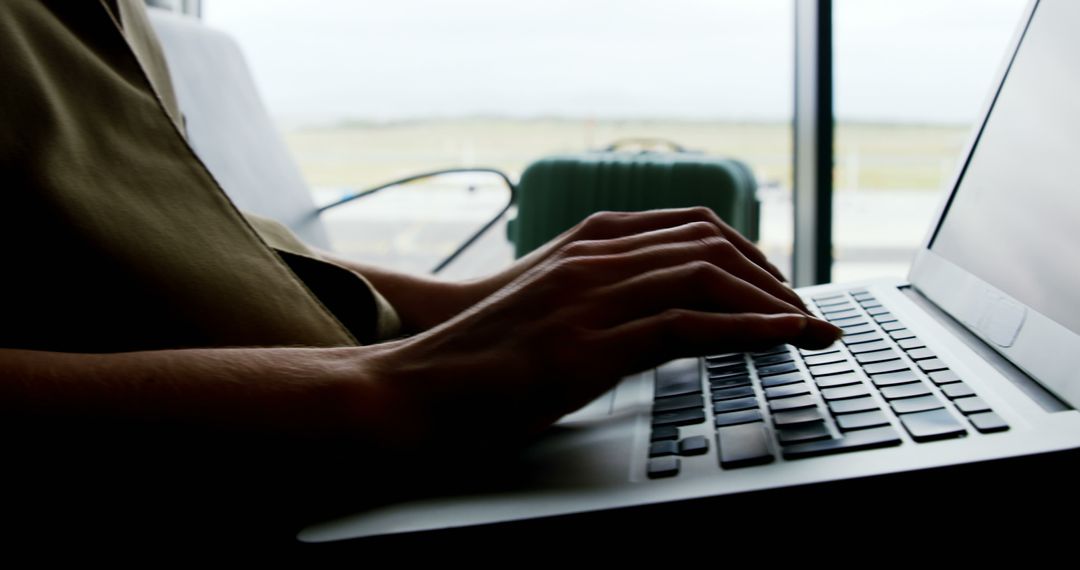 Close-Up of Hands Typing on Laptop at Airport Gate