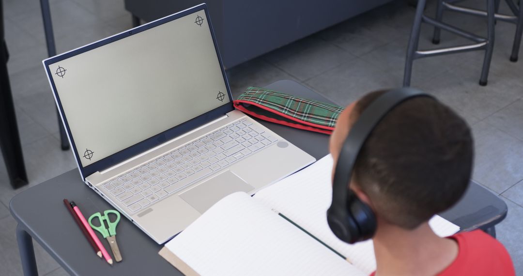 Focused Young Student Wearing Headphones Using Laptop in Classroom