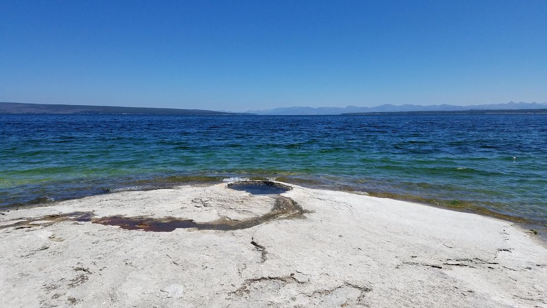Serene Lakeside View with White Rocks and Blue Sky