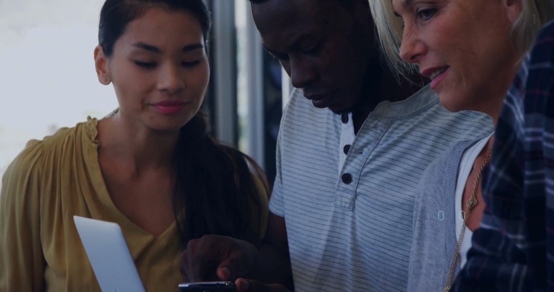Diverse Team Collaborating on Tech Devices in Office Environment