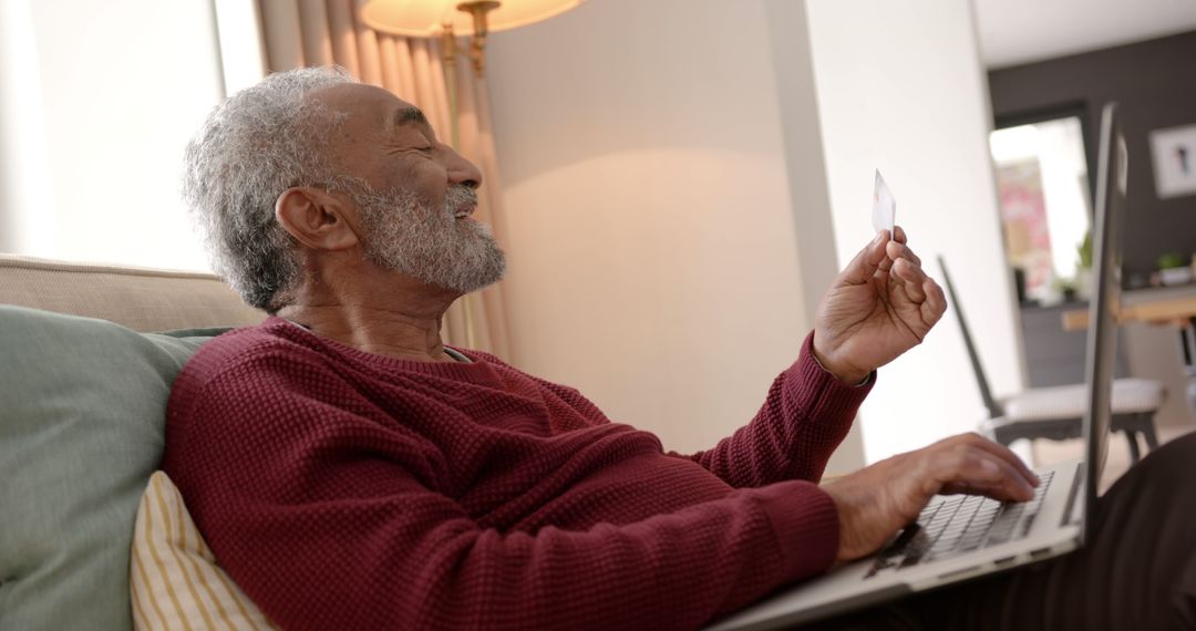 Elderly Man Smiling While Online Shopping with Credit Card on Laptop - Free Images, Stock Photos and Pictures on Pikwizard.com