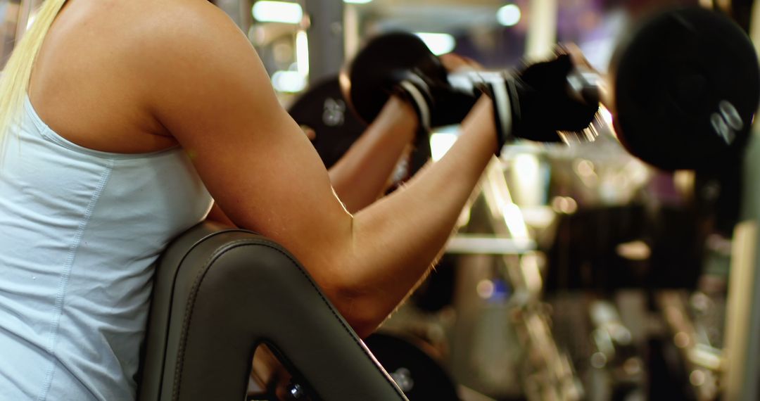 A dedicated young woman intensively performs bicep curls at the gym. - Free Images, Stock Photos and Pictures on Pikwizard.com