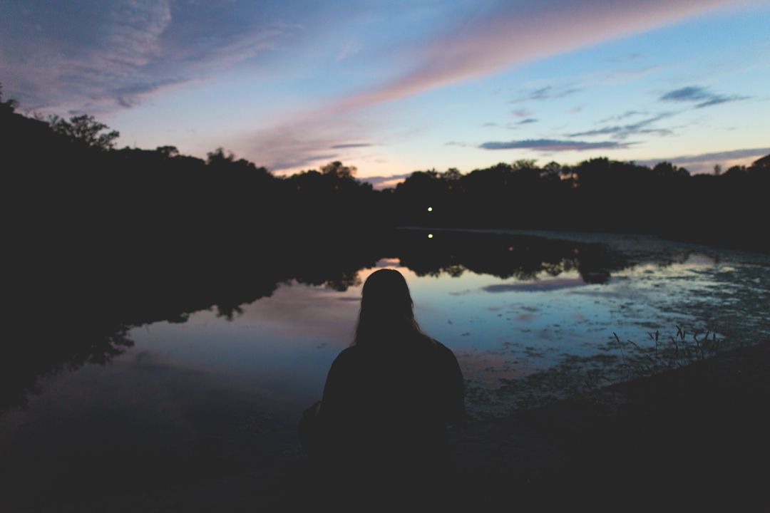 Silhouette of Person by Tranquil Lake at Sunset - Free Images, Stock Photos and Pictures on Pikwizard.com