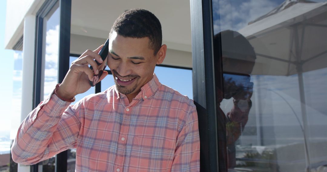 Smiling Man Talking on Smartphone on Seaside Terrace