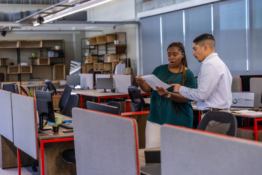 Diverse Coworkers Discussing Report in Open-Plan Office