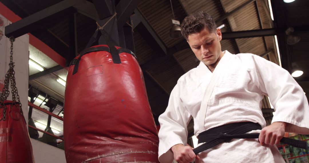 Martial Artist Tying Belt in Gym with Punching Bags - Free Images, Stock Photos and Pictures on Pikwizard.com