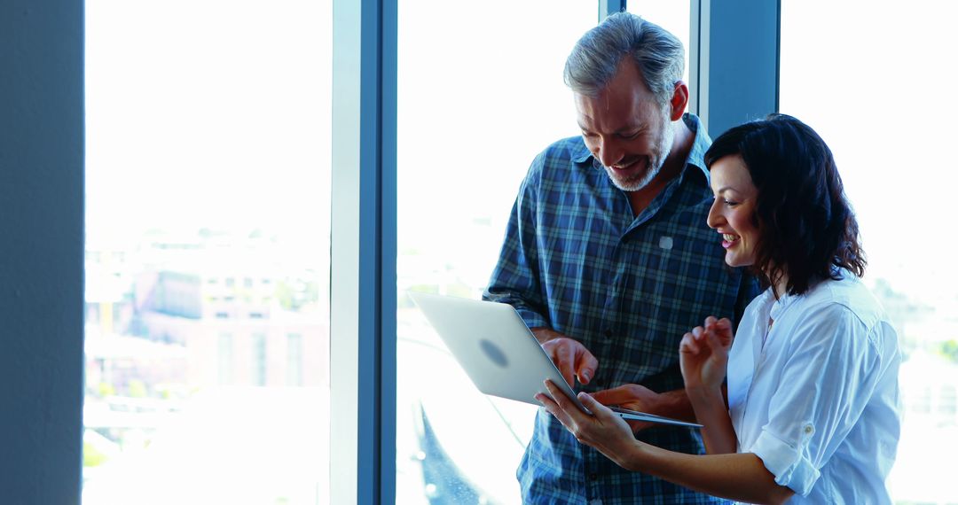 Smiling Business Team Collaborating on Laptop in Office Environment