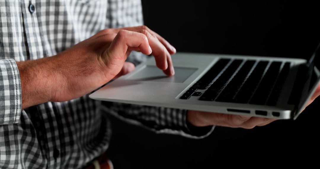 Person Using Laptop with Checkered Shirt Against Dark Background - Free Images, Stock Photos and Pictures on Pikwizard.com