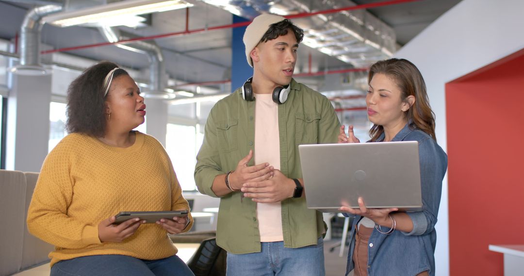 Multicultural team collaborating in modern open office lounge with laptop and tablet