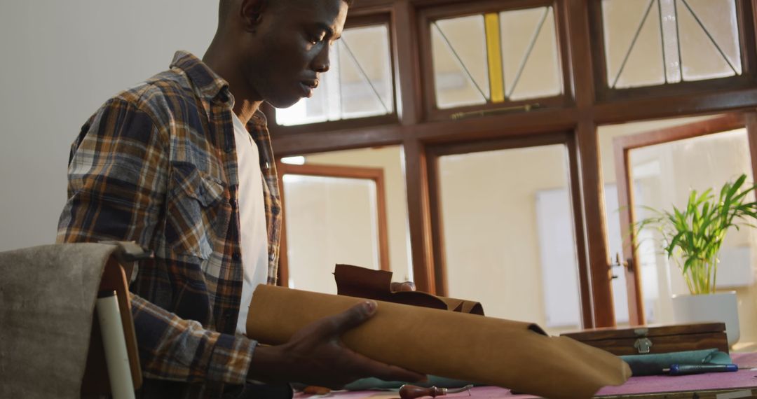 African American Craftsman Examining Leather Rolls in Workshop