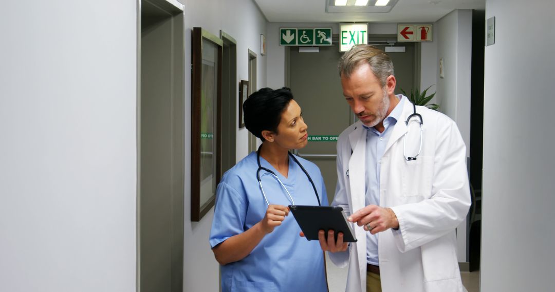 Doctors Discussing Patient Information in Hospital Corridor - Free Images, Stock Photos and Pictures on Pikwizard.com