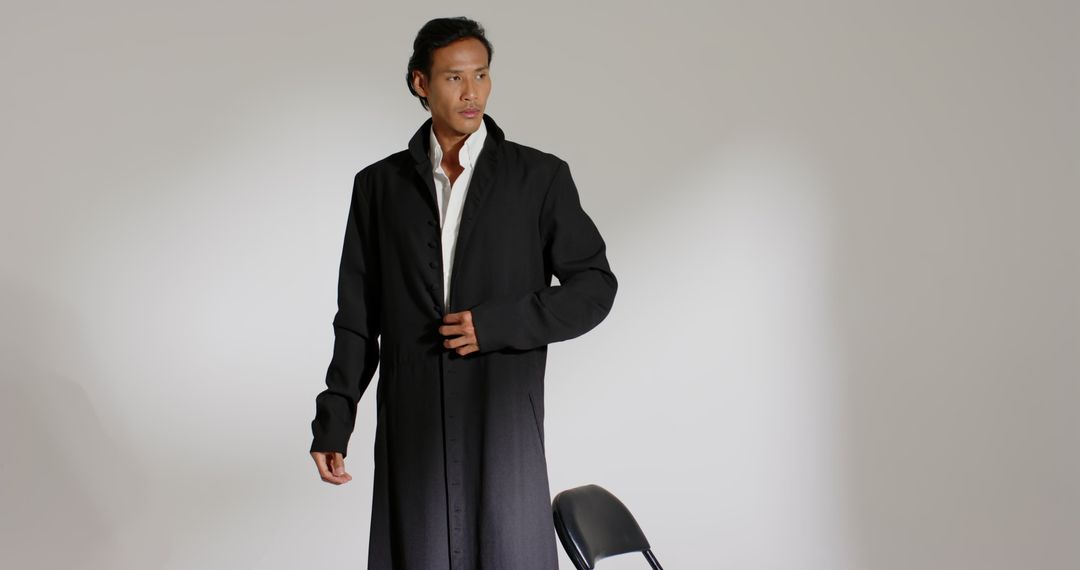 Stylish Man in Long Black Coat Looking Confident in Minimalist Studio