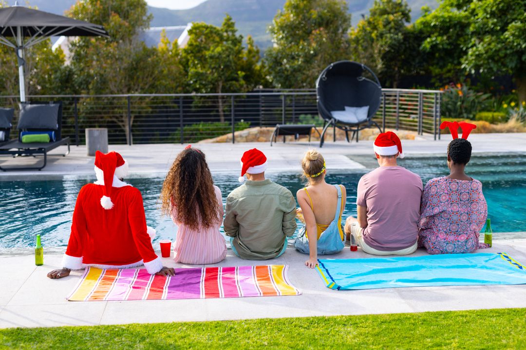 Rear view of diverse group of friends in chirstmas hats sitting by pool with drinks, copy space - Free Images, Stock Photos and Pictures on Pikwizard.com