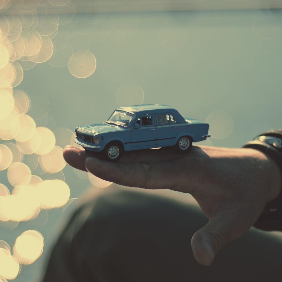 Person Holding Vintage Blue Toy Car with Sun Reflecting on Water - Free Images, Stock Photos and Pictures on Pikwizard.com