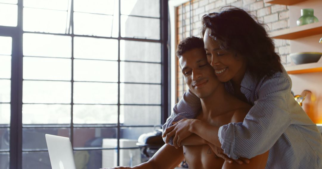 Couple Embracing While Using Laptop in Modern Home