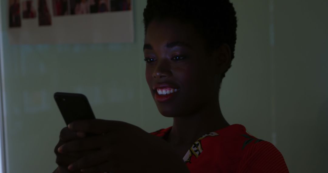 Woman Smiling While Using Smartphone in Dimly Lit Room - Free Images, Stock Photos and Pictures on Pikwizard.com