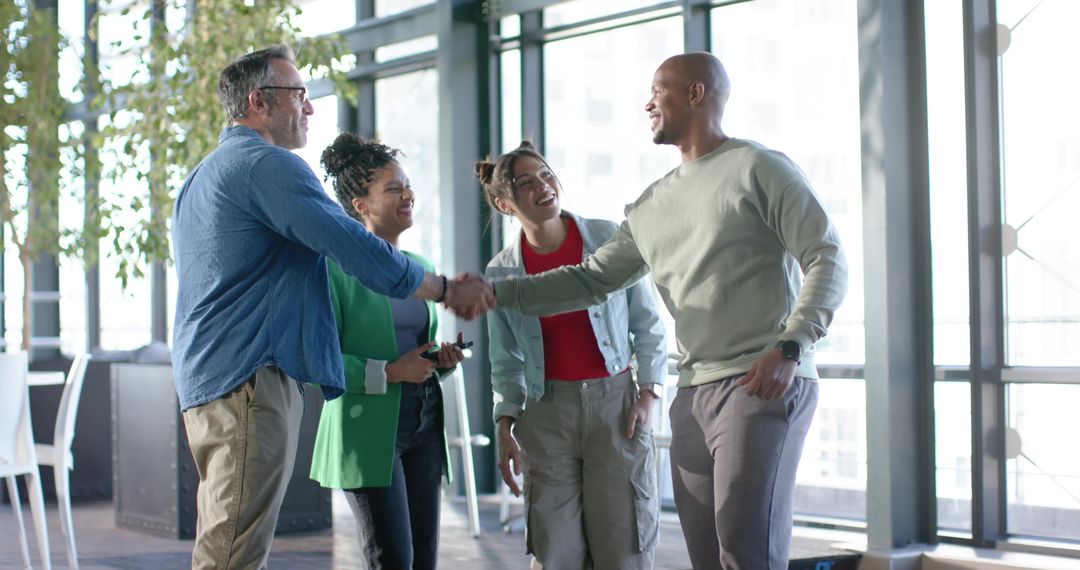 Multicultural Team Shaking Hands in Modern Office While Colleagues Smile and Connect