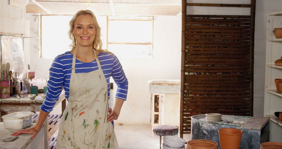 Smiling Female Artist in Her Pottery Studio Wearing Apron - Free Images, Stock Photos and Pictures on Pikwizard.com