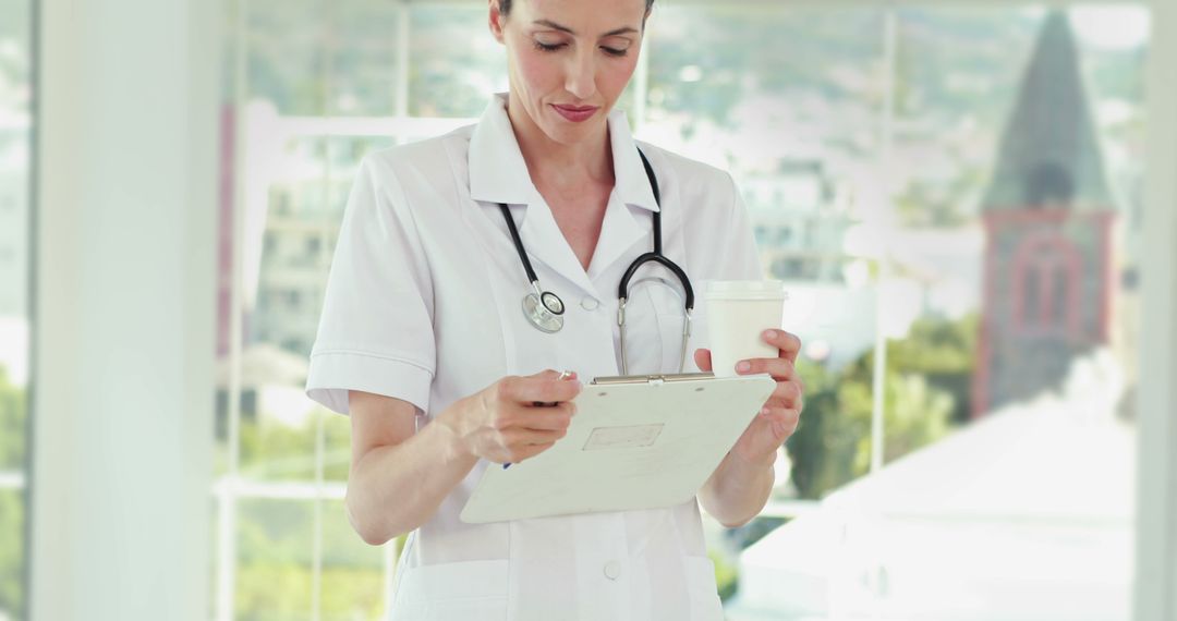 Focused Nurse Reading Chart with Coffee at Hospital Ward - Free Images, Stock Photos and Pictures on Pikwizard.com