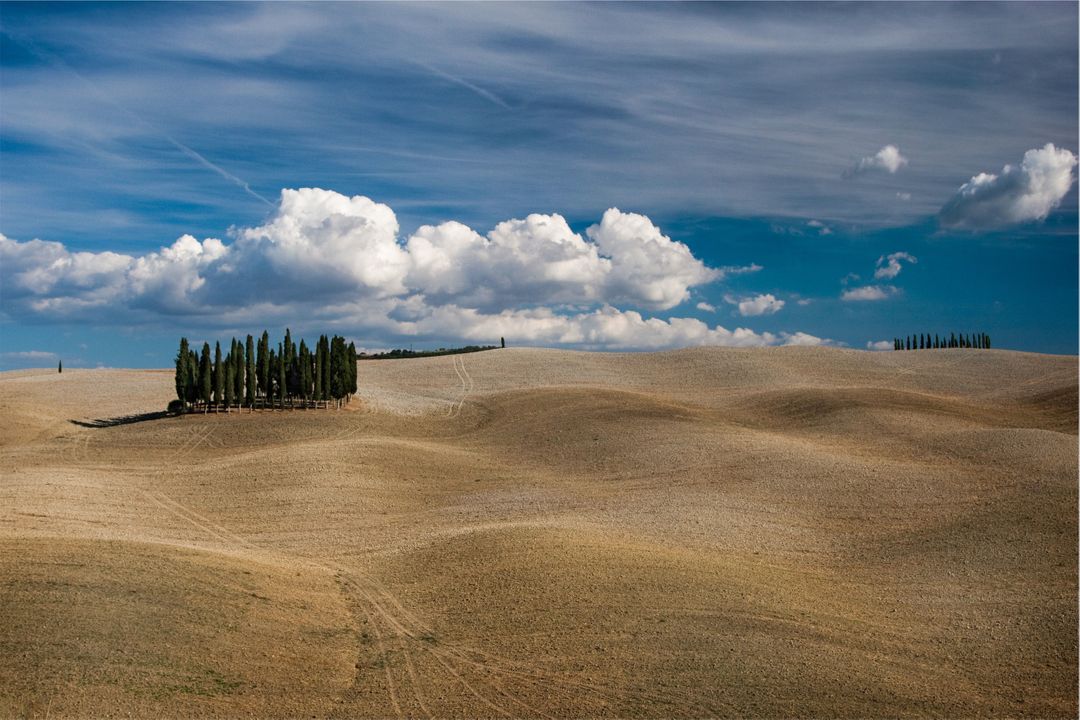 Rolling Hills and Cypress Trees under Blue Sky with Clouds in Tuscany - Free Images, Stock Photos and Pictures on Pikwizard.com