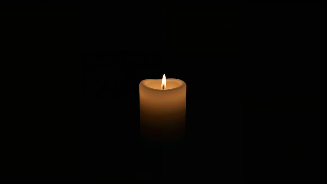 Glowing wax candle casting ambient warm glow in darkness for condolences