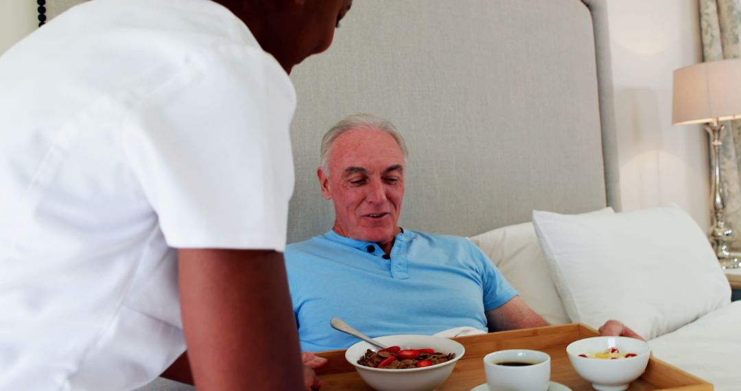 Caregiver serving meal to senior man in bed for breakfast - Free Images, Stock Photos and Pictures on Pikwizard.com