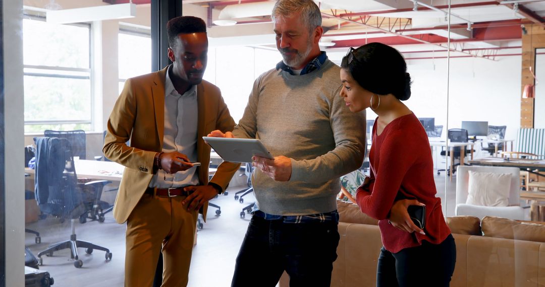 Team Collaboration in Modern Office with Diverse Group Discussing Ideas on Tablet