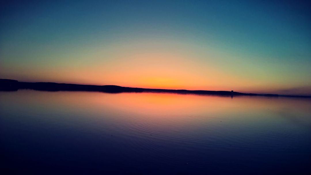 Serene Sunset Over Calm Lake with Distant Horizon - Free Images, Stock Photos and Pictures on Pikwizard.com