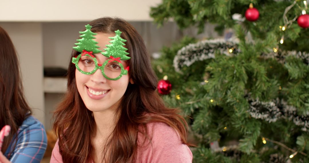 Woman Wearing Festive Christmas Tree Glasses Smiling by Decorated Tree