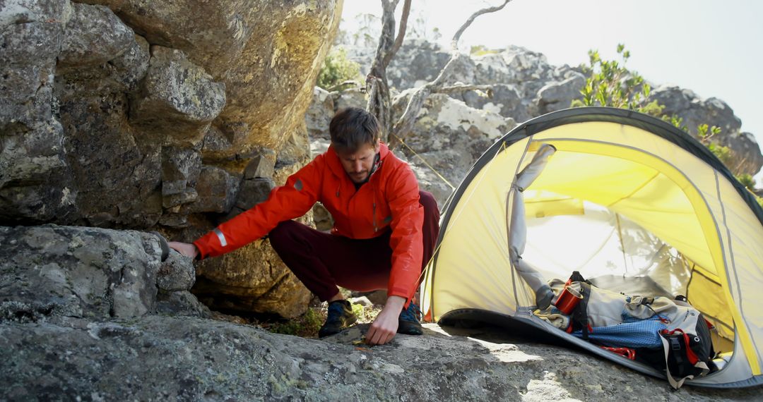 Male Hiker Setting Up Camp Near Rocky Terrain and Tent - Free Images, Stock Photos and Pictures on Pikwizard.com