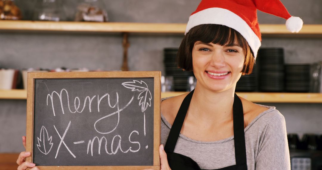 Smiling Woman in Santa Hat Holding Merry X-Mas Chalkboard Sign - Free Images, Stock Photos and Pictures on Pikwizard.com