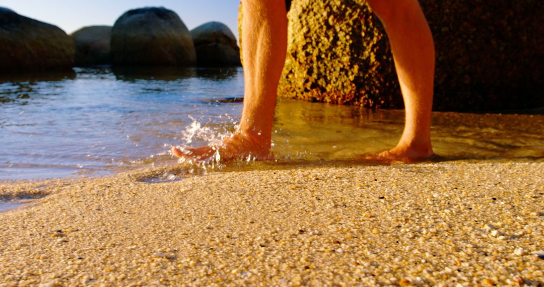 Person Walking in Shallow Water Near Rocky Shore at Sunset - Free Images, Stock Photos and Pictures on Pikwizard.com