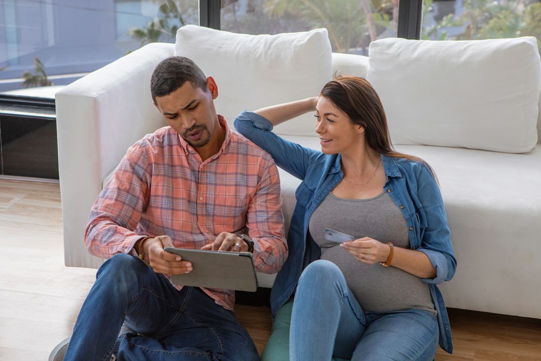 Expecting Couple Using Tablet with Credit Card in Cozy Home Setting