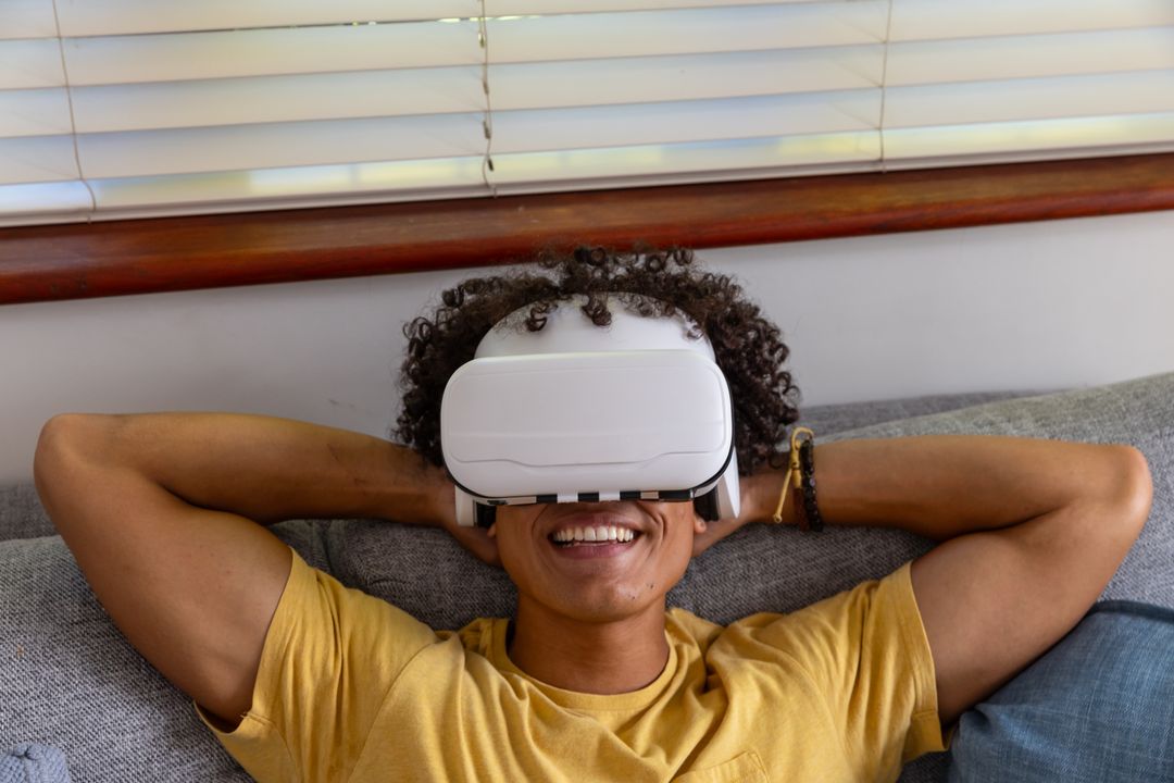 Reclining Young Man Enjoying Virtual Reality Headset on Sofa for Relaxation