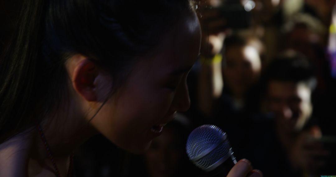 Young Asian Female Singer Captivating Diverse Audience During Performance - Free Images, Stock Photos and Pictures on Pikwizard.com