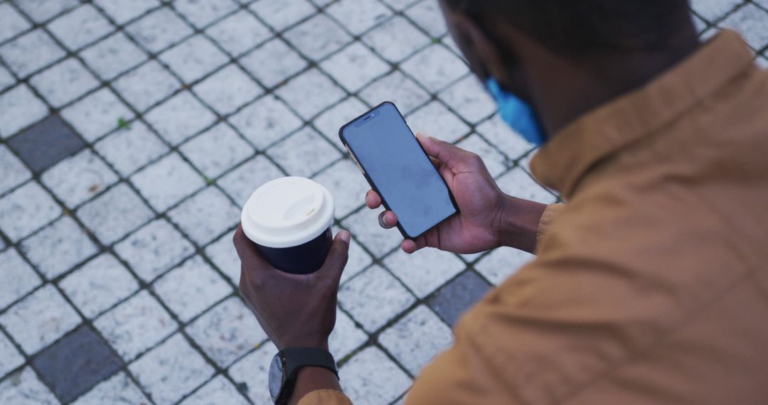 Man Checking Smartphone Outdoors with Coffee Cup - Free Images, Stock Photos and Pictures on Pikwizard.com