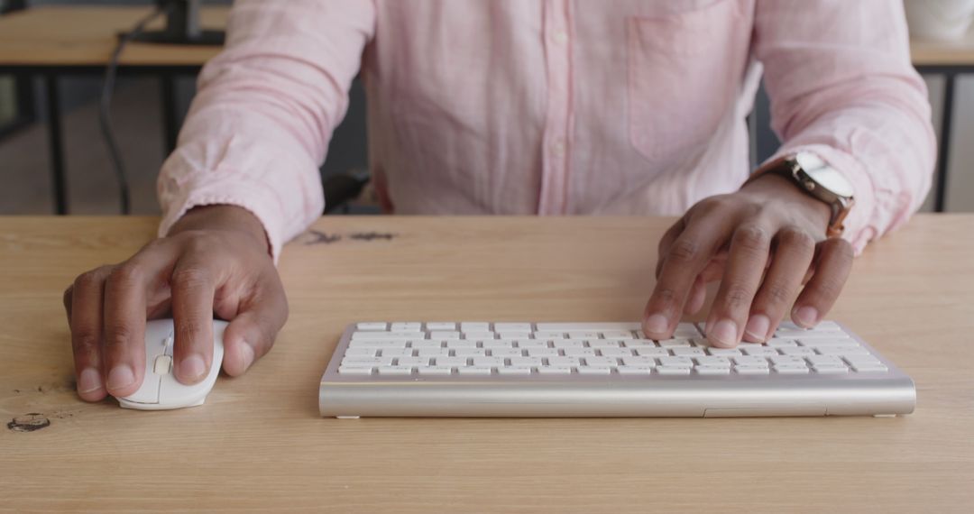 Close-up of Businessperson Typing at Desk with Keyboard and Mouse