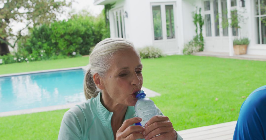 Senior Woman Drinking Water by Poolside in Backyard - Free Images, Stock Photos and Pictures on Pikwizard.com