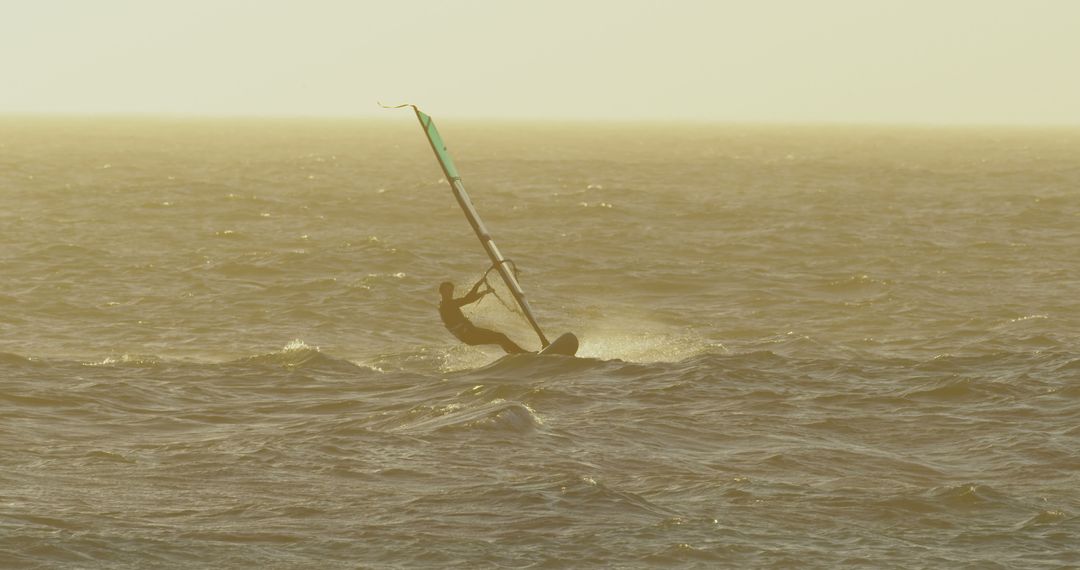 Windsurfer riding waves at sunset, golden sky and water - Free Images, Stock Photos and Pictures on Pikwizard.com