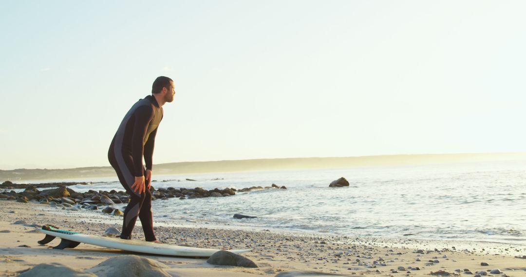 Male Surfer Contemplating Waves on Beach at Sunrise - Free Images, Stock Photos and Pictures on Pikwizard.com