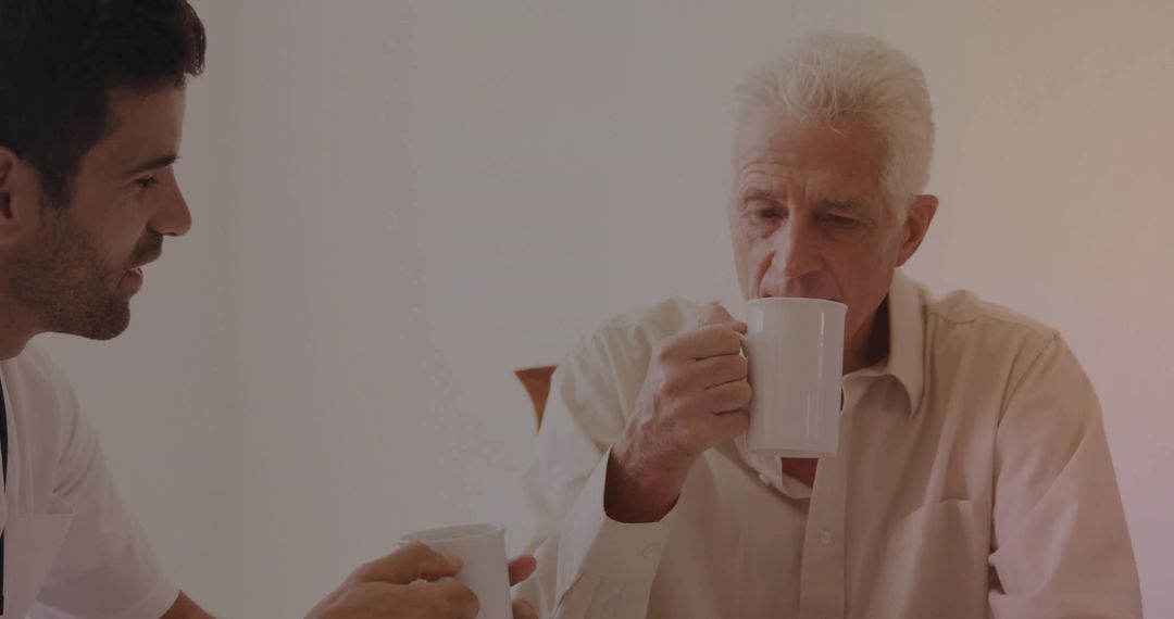Senior Man Enjoying Coffee with Caregiver at Home