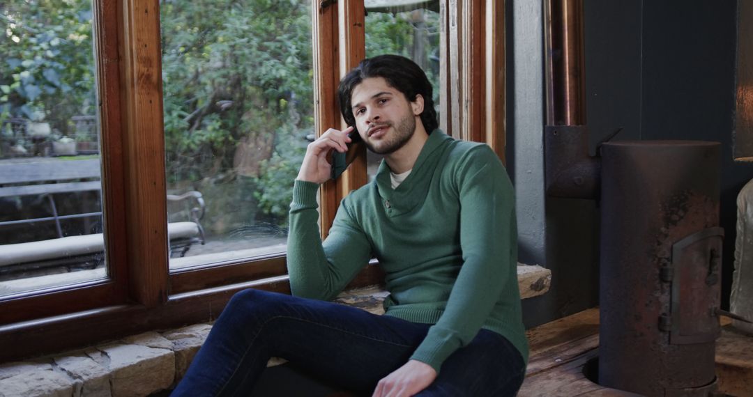 Man Relaxing by Window Using Smartphone in Cozy Home - Free Images, Stock Photos and Pictures on Pikwizard.com