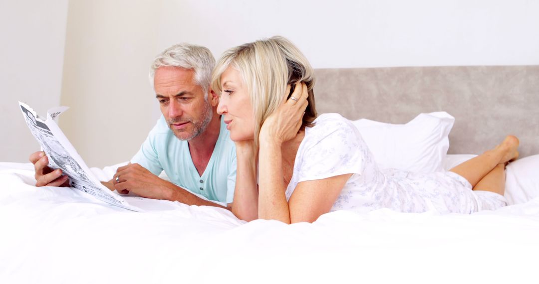 Senior Couple Relaxing in Bed Reading Newspaper - Free Images, Stock Photos and Pictures on Pikwizard.com