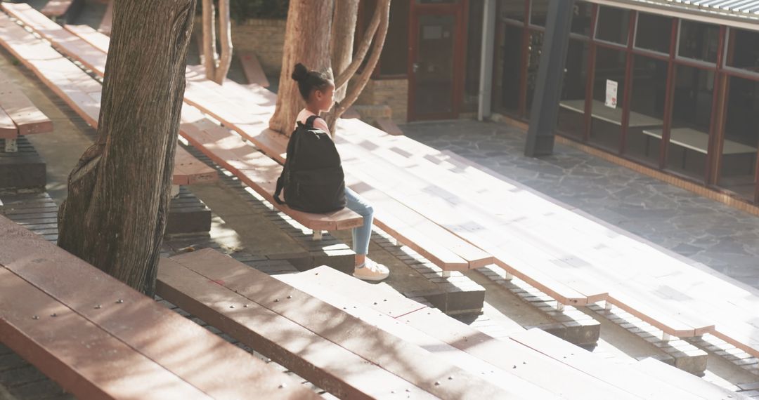 Girl Sitting on Bench Surrounding Tree in Courtyard Daylight