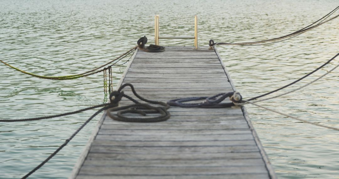 Wooden Dock Extending Over Calm Water with Ropes at Sunset - Free Images, Stock Photos and Pictures on Pikwizard.com