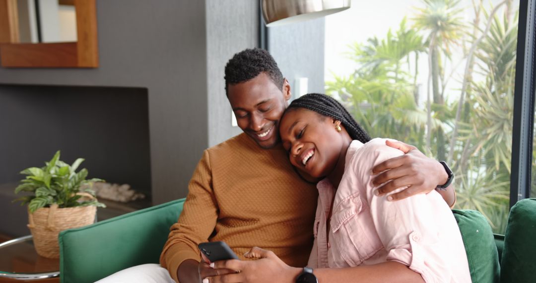 Joyful Couple Relaxing on Couch with Smartphone