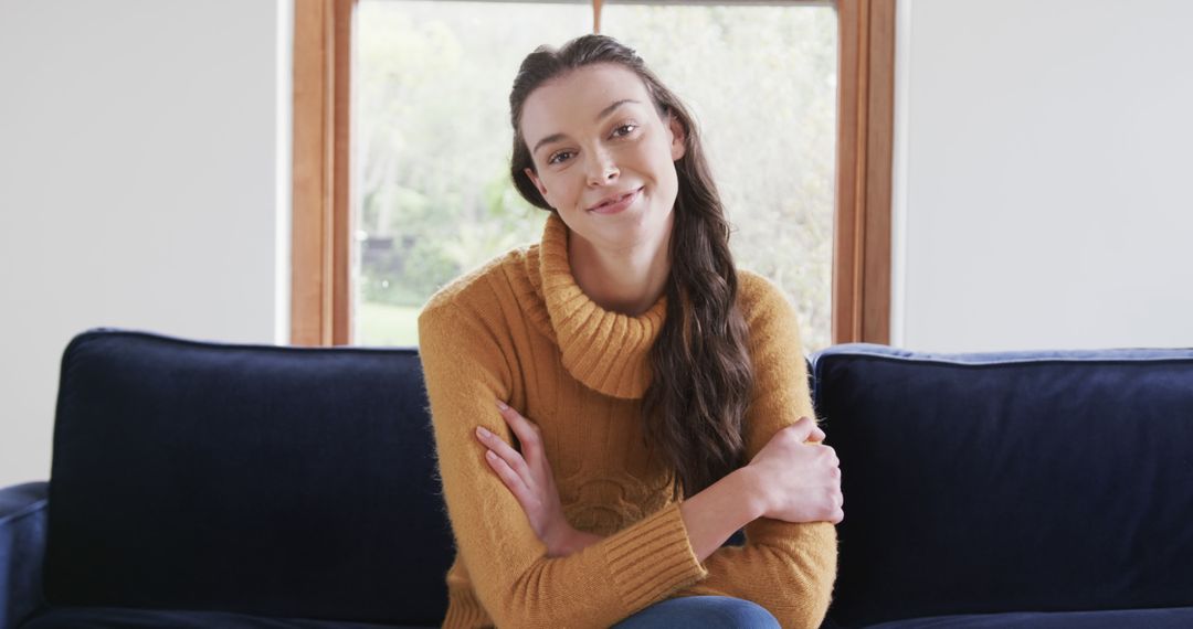 Young Woman Sitting on Navy Blue Sofa Smiling in Cozy Living Room - Free Images, Stock Photos and Pictures on Pikwizard.com