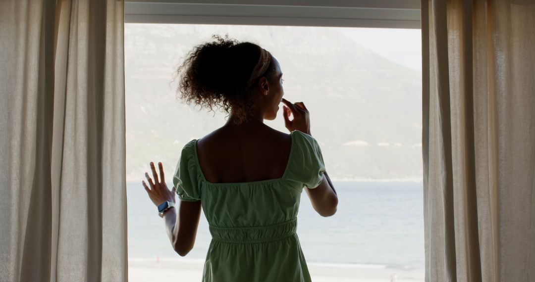 Woman Enjoying Ocean View from Window with Smartwatch